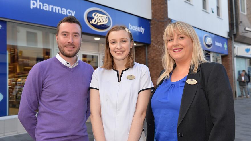 Three employees stood in front of Boots store