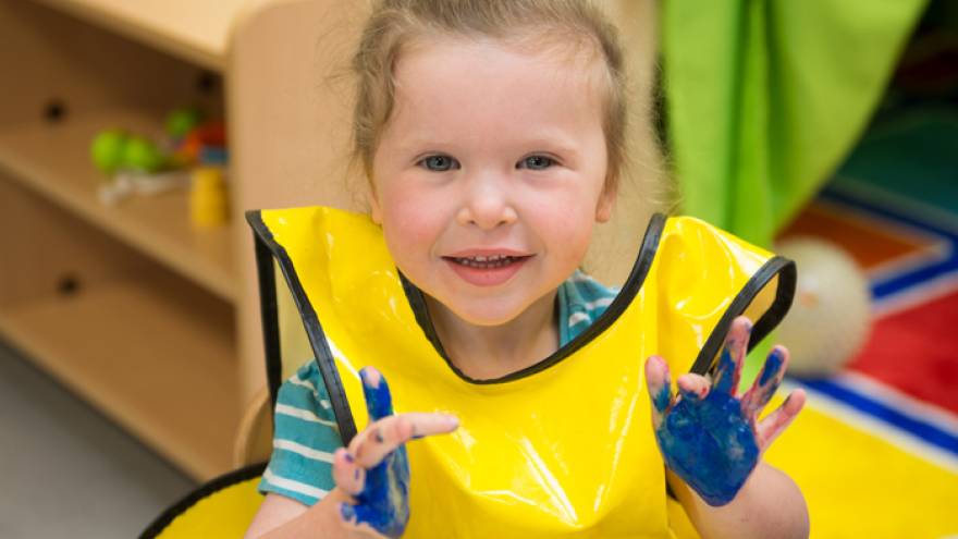 Young girl in nursery playing with finger paints
