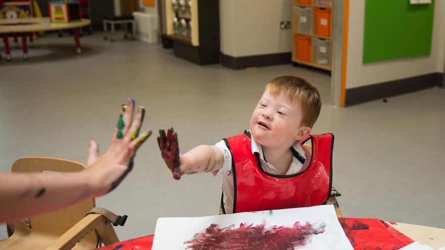 Young boy in nursery playing with paints