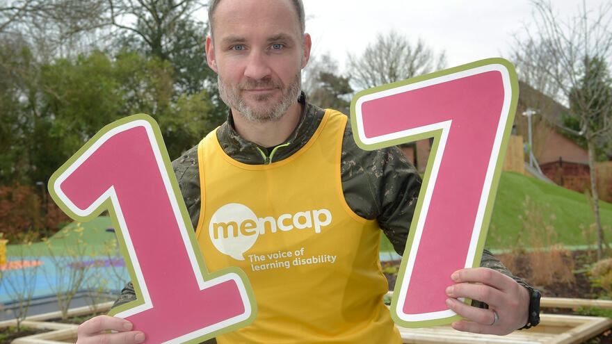 Man holding up the numbers "1" and "7"