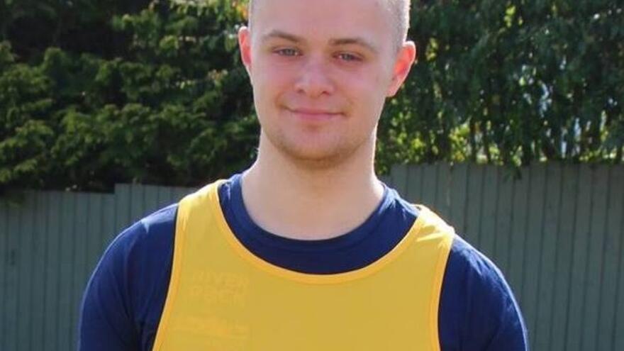 Man stood outside wearing yellow Mencap running jersey