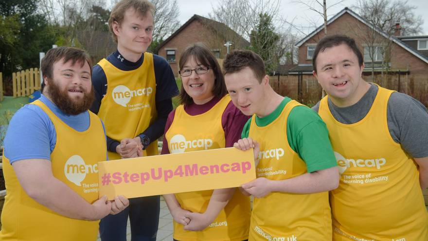 Group of people in yellow Mencap running vests holding a #StepUp4Mencap sign