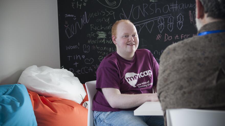 Man sat in a chair in front of a chalk board