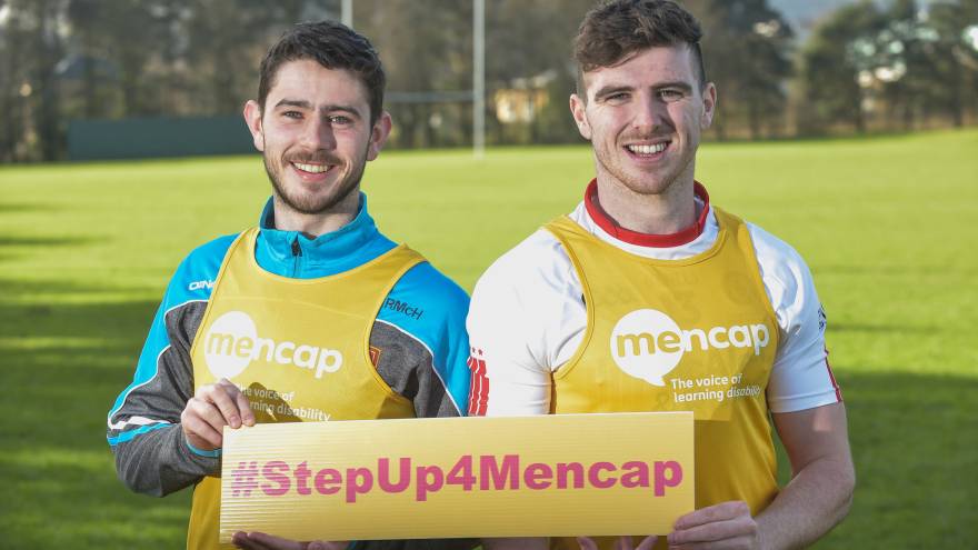 Two men stood outside holding a #StepUp4Mencap banner