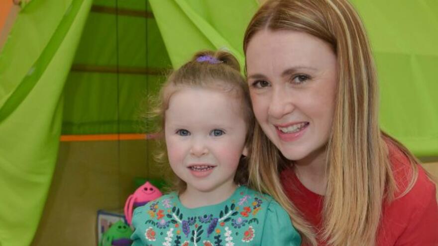 Woman with long blonde hair next to her young daughter.