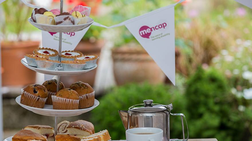 Cake stand with cakes and bunting on a table outside