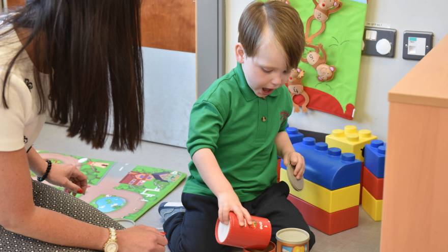 Young boy with woman playing with toys in nursery
