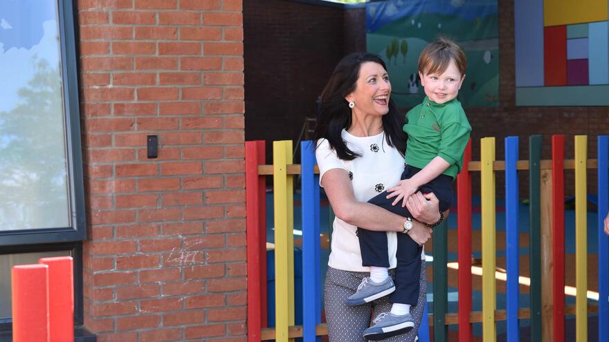 Woman in play area holding hear young son