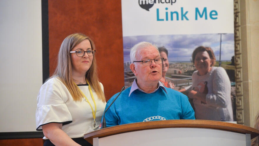 Man and woman stood together at podium with microphone giving a speech