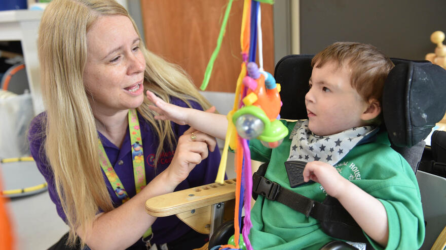 Young boy sat in chair playing with woman with blonde hair who is next to him