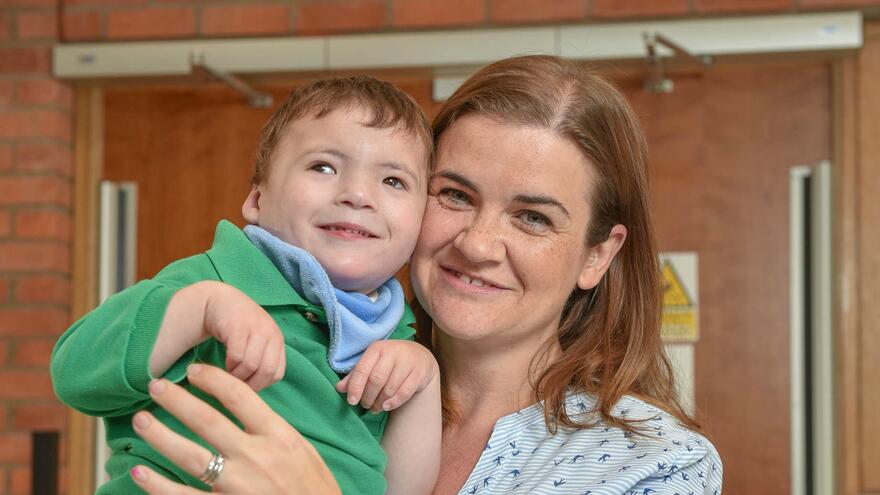 Young boy being held up by woman who is smiling