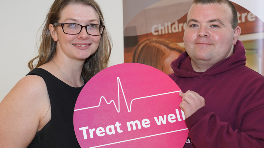 Man and woman holding pink Treat me well sign.