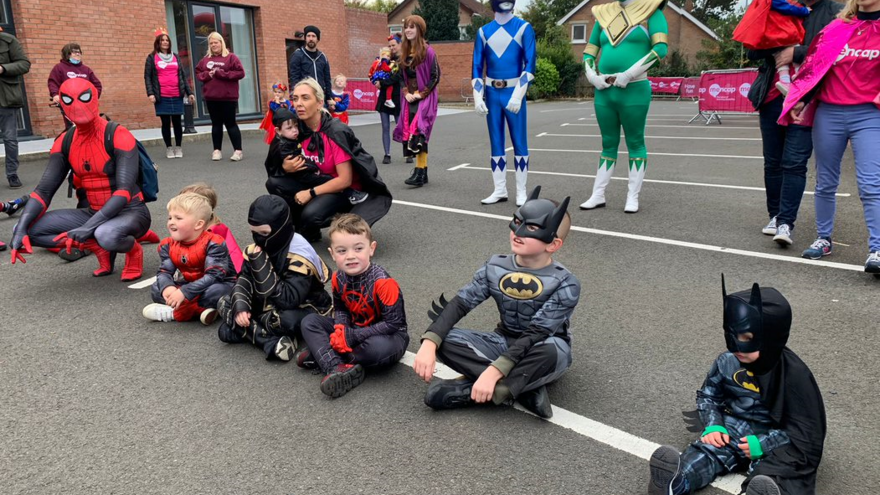 Adults and children dressed as superheros outside the Mencap Centre building