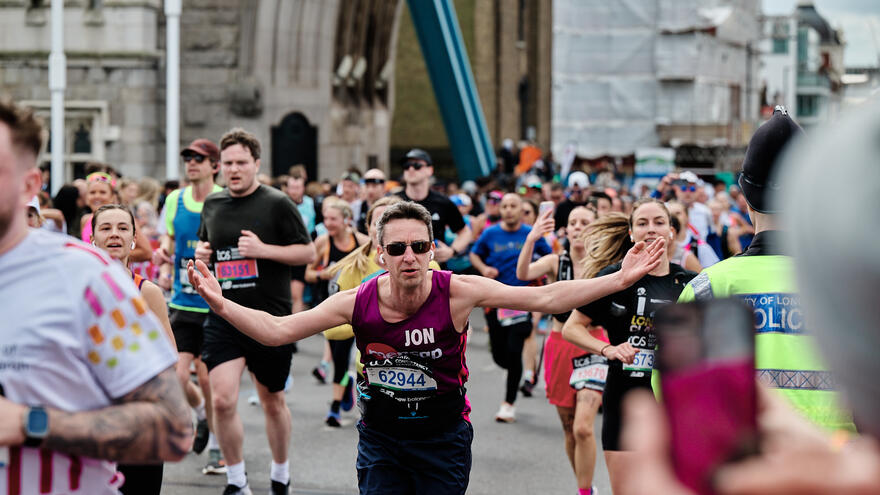 male runner running with wide hands open while cheering
