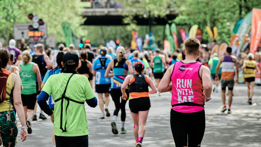 Man wearing a Mencap running vest with his back to us, the vest reads Run With Me