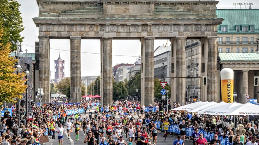 People running through the brandenburg gate towards the end of the marathon.