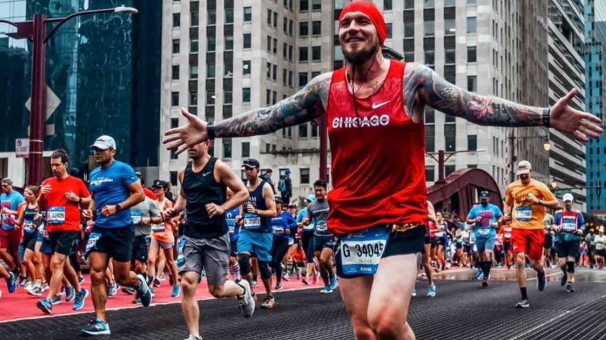 Man in red with arms out running the Chicago Marathon