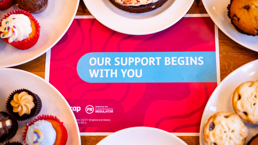 Our support begins with you sign with plates of cakes