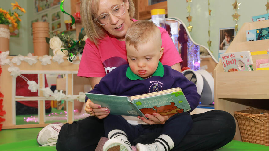 Child reading book with adult on the floor