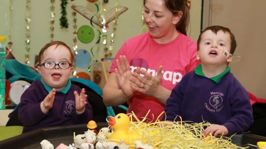 Woman clapping hands with two children at a table