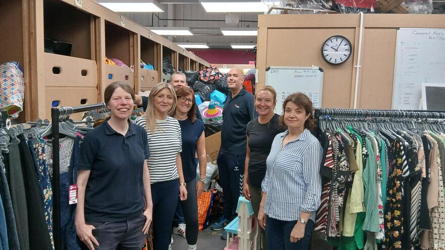 corporate volunteers standing next to donations in a charity shop
