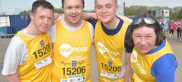 Group of four people stood outside wearing yellow Mencap running vests
