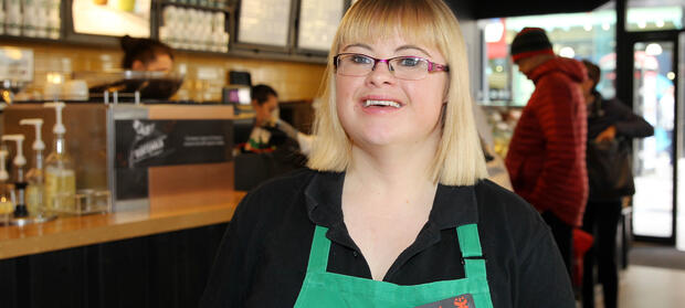 Woman wearing an apron stood in a restaurant