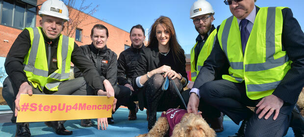 Group of people kneeling outside with George the dog and holding a #StepUp4Mencap sign