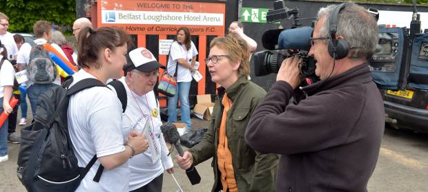 Two being being interviewed by a woman with a microphone and a man holding a camera