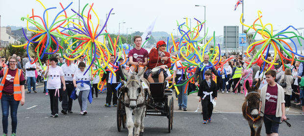 People waving colourful decorations, taking part in a parade outside