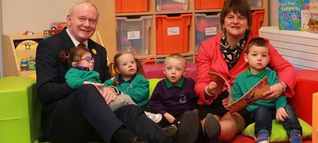 Two adults sat with four young children in nursery, reading books