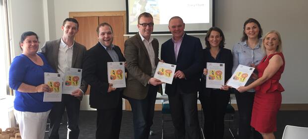 Eight people stood in meeting room holding copies of parents guide