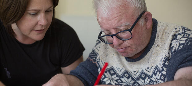 A man and woman sat together at a table drawing with felt tip pens
