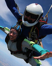 Two people strapped together doing a skydive.