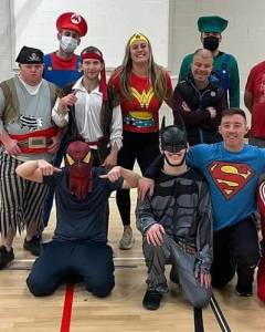 group of people in superhero costumes gathered in a gym