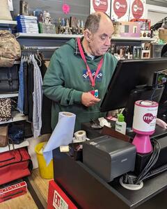 A man in a Mencap shop using the till
